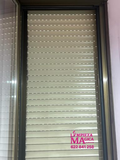 Limpieza Persianas enrollables de color beige en una ventana.